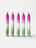 Five taper candles with a vertical ombré color design of pink, white, and light green, standing upright against a plain light gray background.