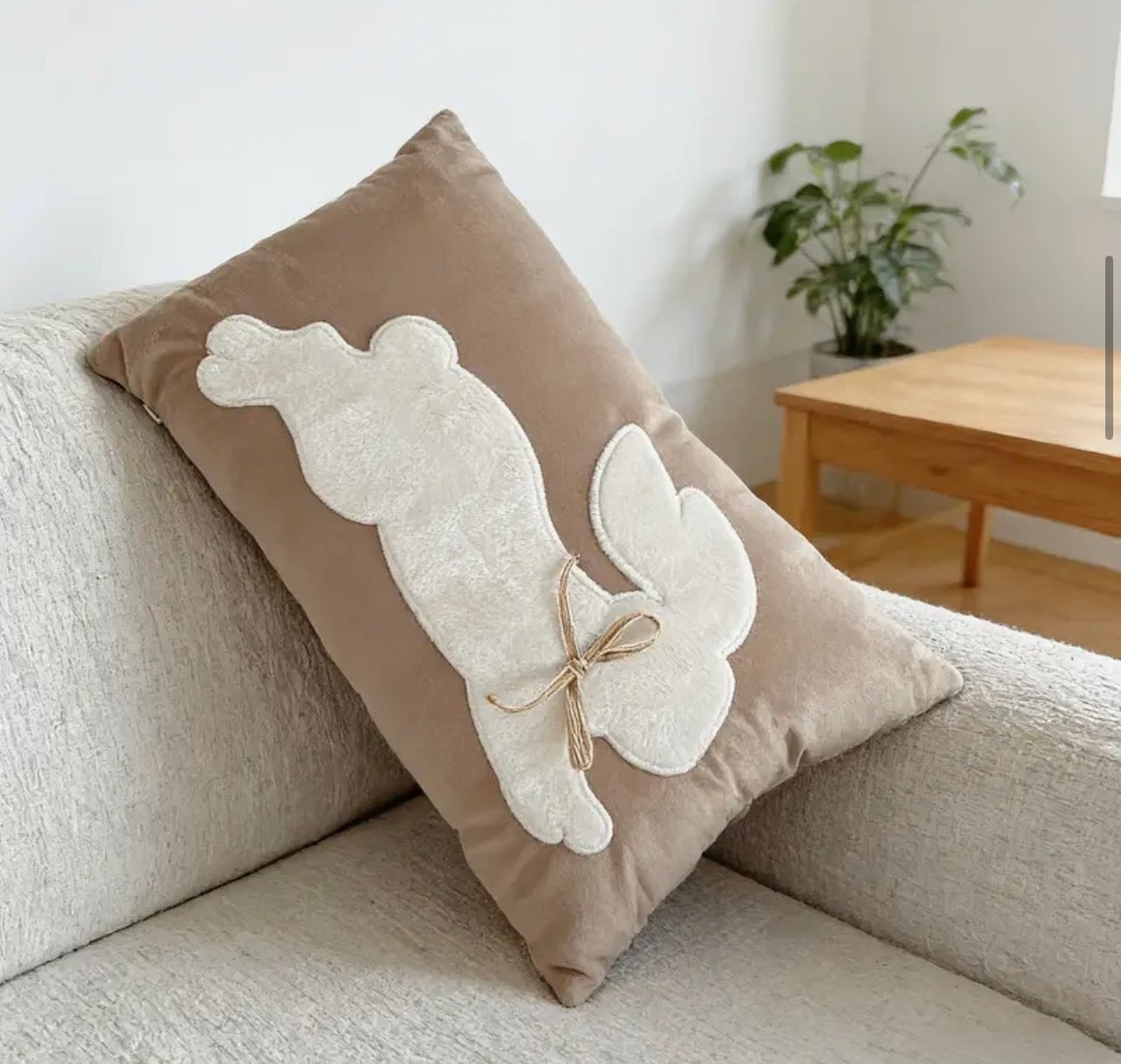 Decorative pillow with angel wings on a beige sofa in a living room setting.