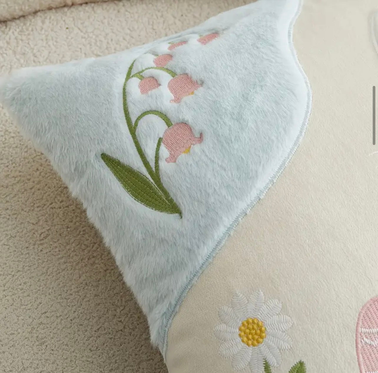 Embroidered pillow with floral design on a beige surface
