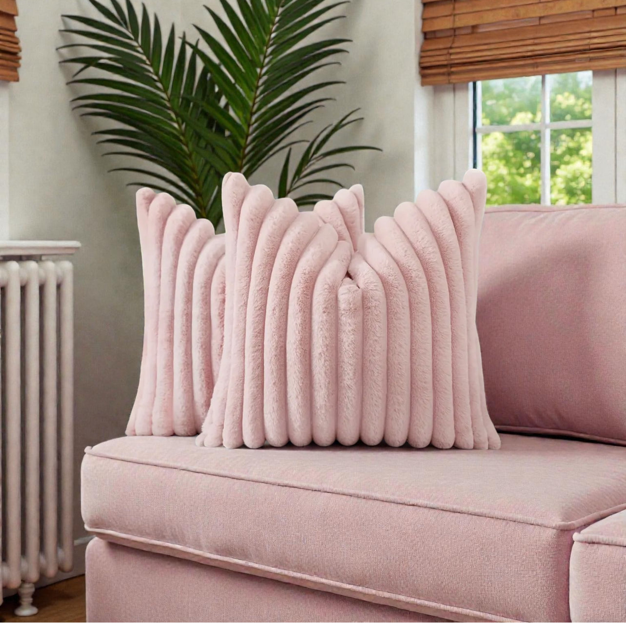 Pink textured pillows on a pink sofa with a plant and window in the background