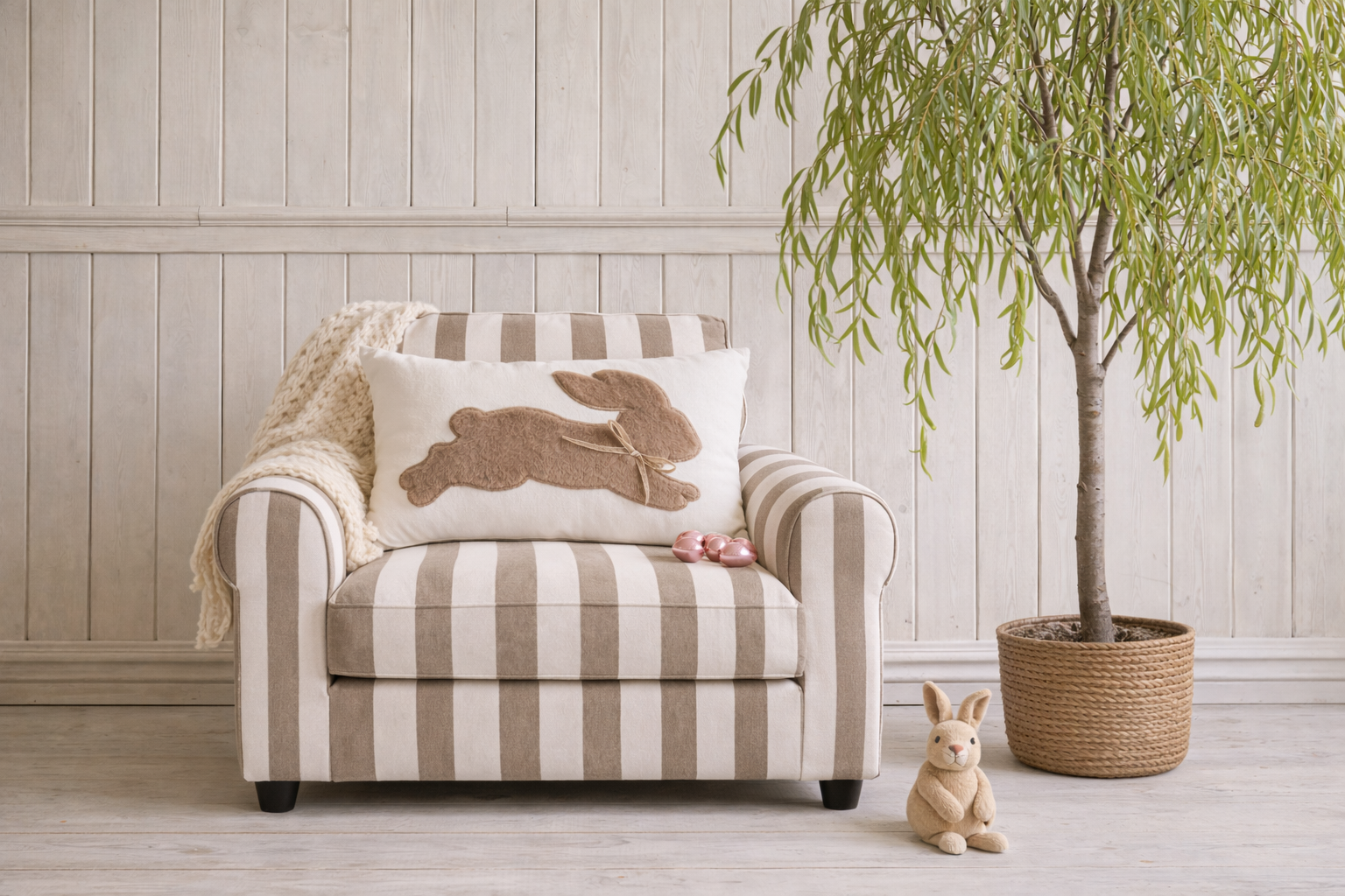 Striped armchair with decorative pillow and rabbit design in a room with wooden floor and wall.