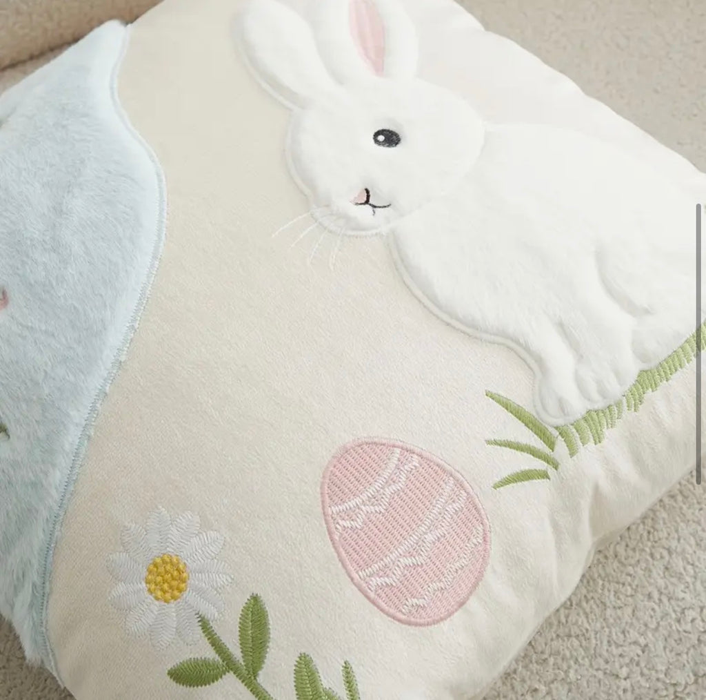 Decorative pillow with a bunny and Easter egg design on a neutral background