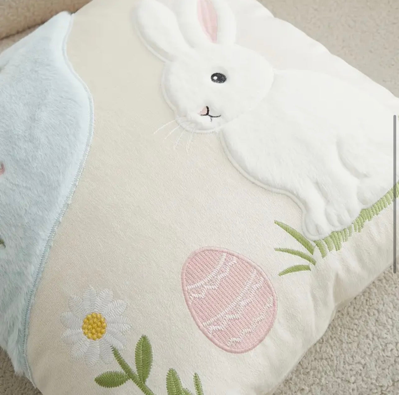 Decorative pillow with a bunny and Easter egg design on a neutral background