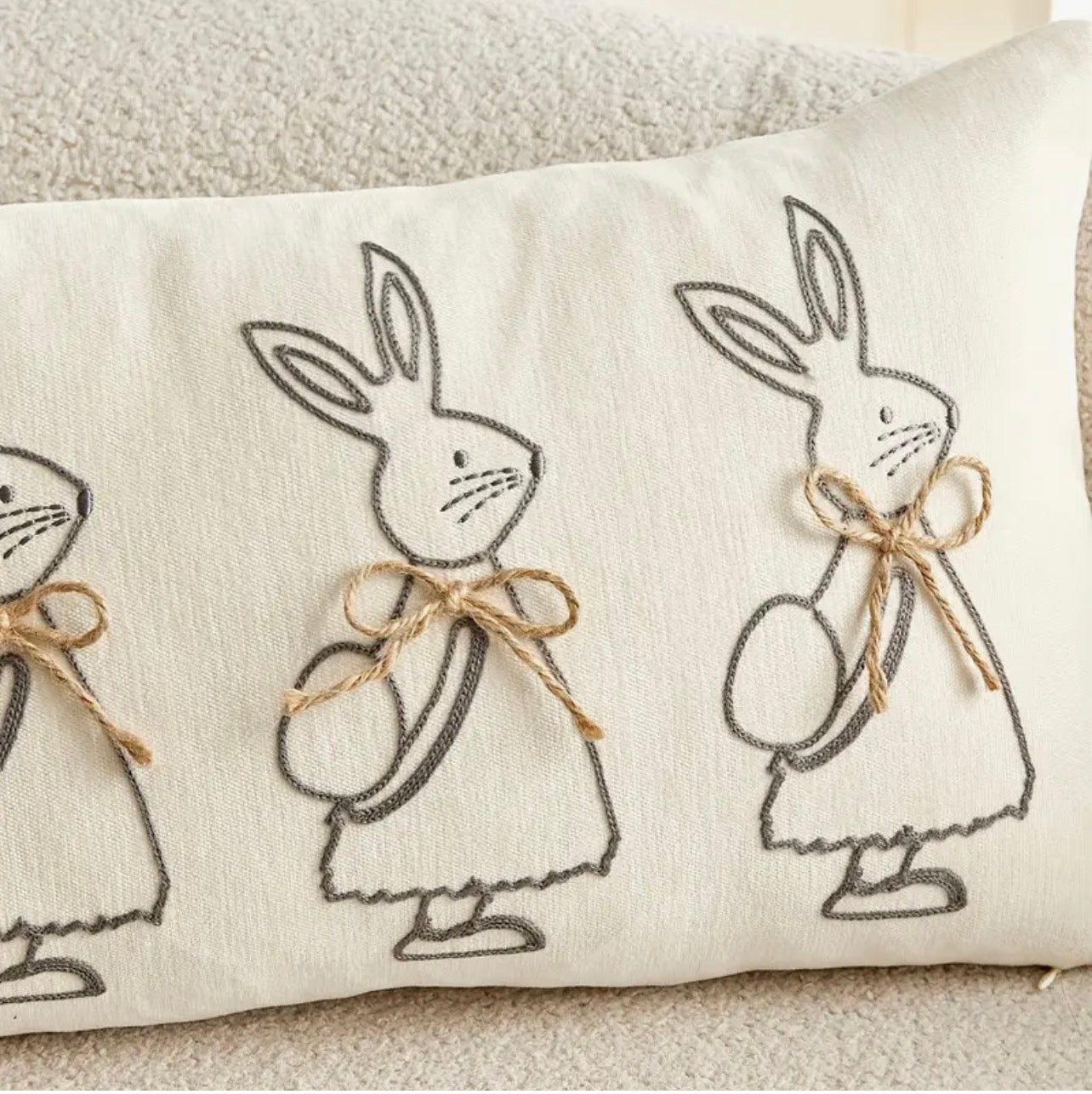Decorative pillow with embroidered bunnies on a neutral background