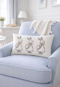 Decorative pillow with rabbit illustrations on a light blue armchair in a bright room.