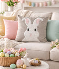 Decorative pillow with a bunny face on a couch with Easter decorations.