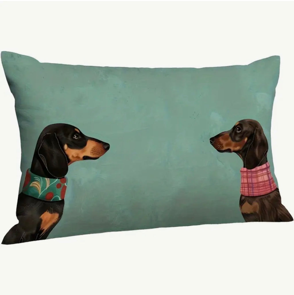 Decorative pillow with two dachshunds wearing colorful sweaters on a teal background