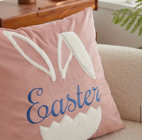 Pink pillow with 'Happy Easter' text and bunny ears on a couch.