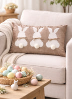 Decorative pillow with bunny designs on a couch, surrounded by Easter eggs and decor.