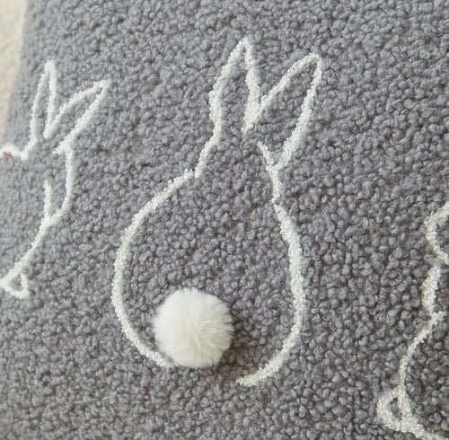 Gray textured pillow with white embroidered design and pom-pom detail