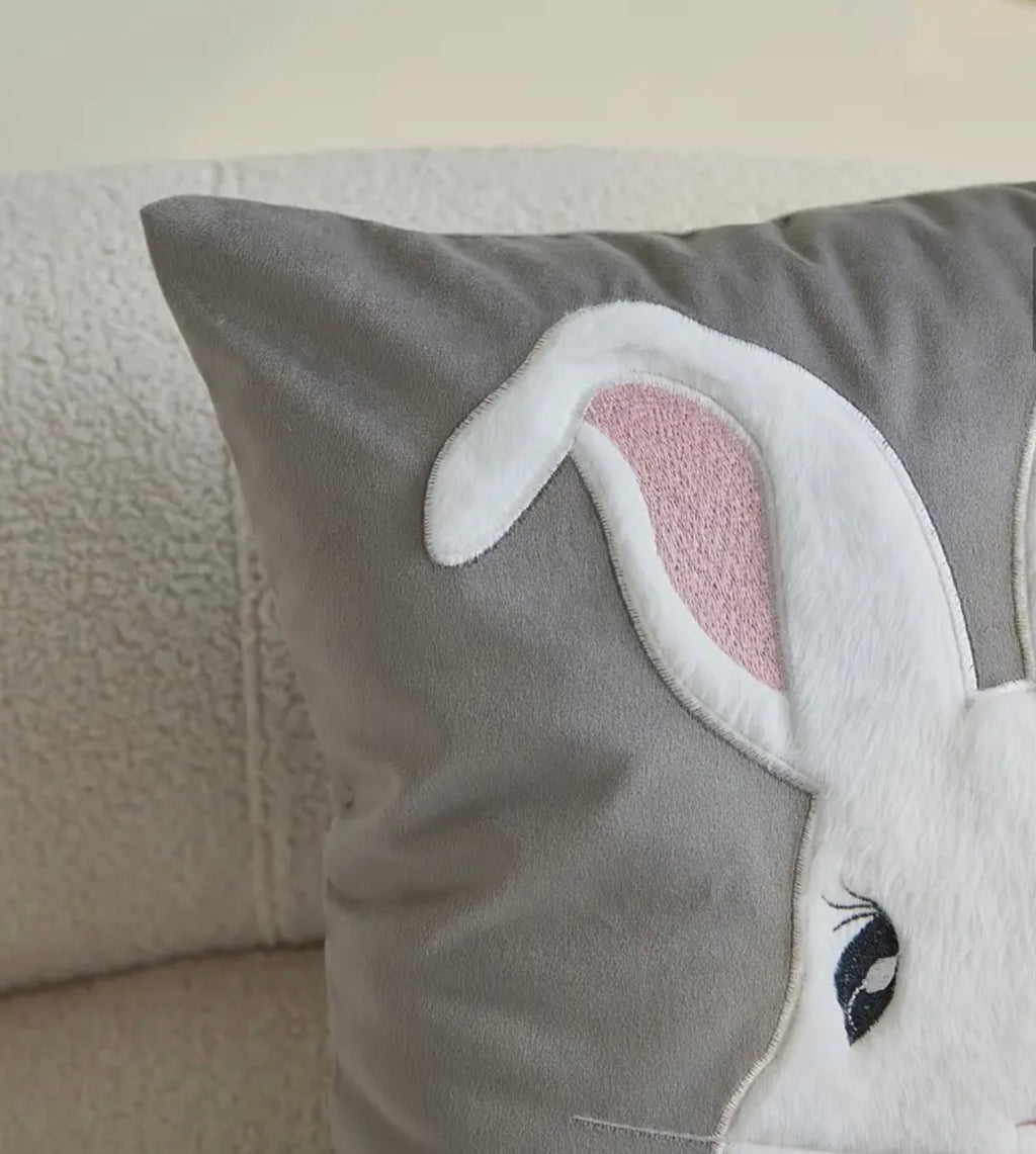 Gray pillow with a rabbit ears design on a neutral background