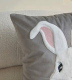 Gray pillow with a rabbit ears design on a neutral background