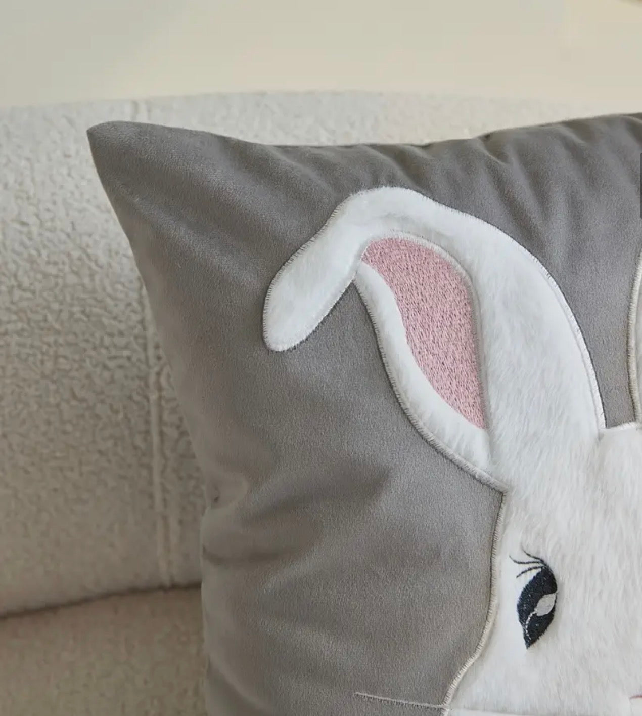 Gray pillow with a rabbit ears design on a neutral background