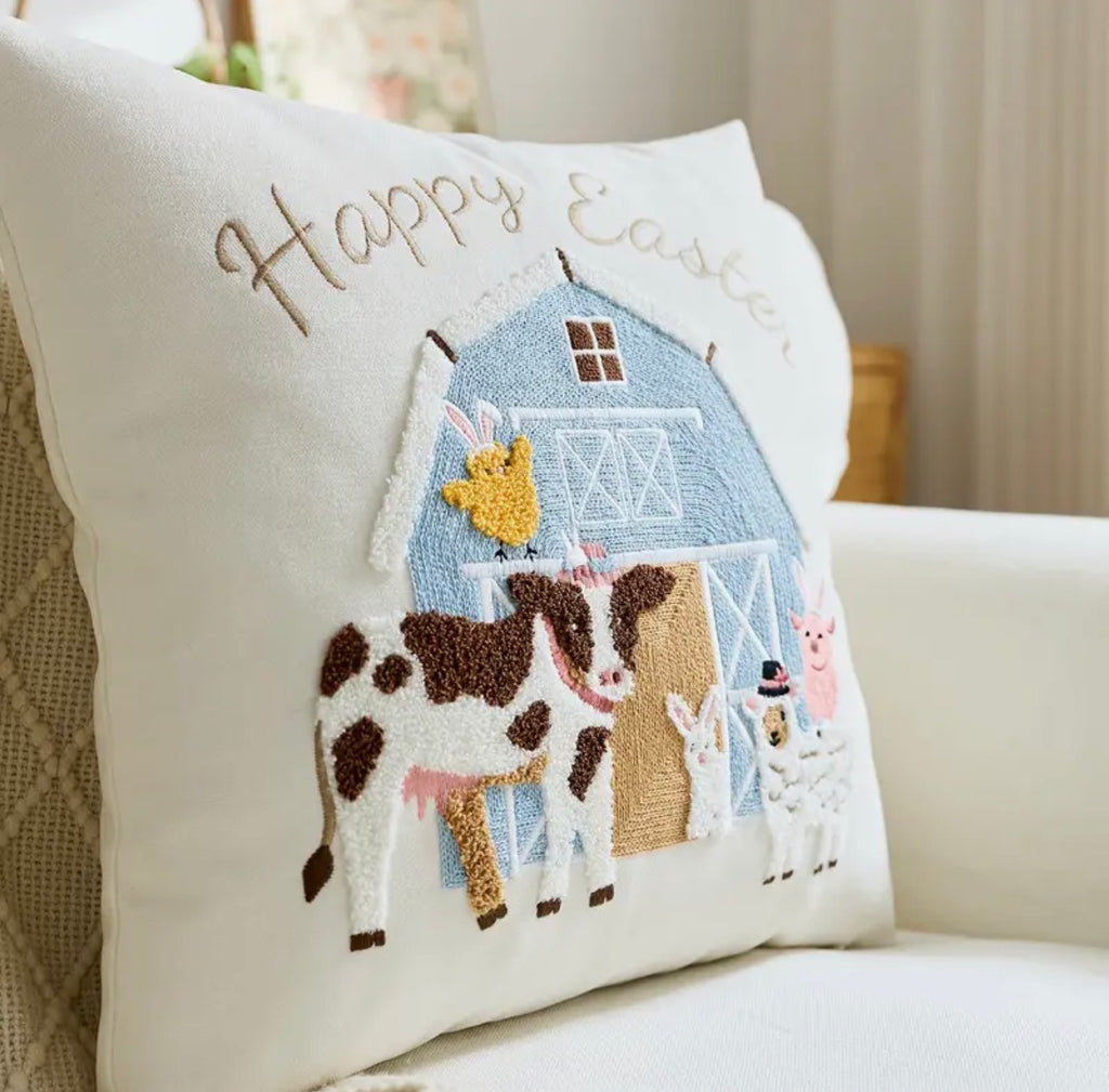 Decorative pillow with farm scene and 'Happy Easter' text on a couch.