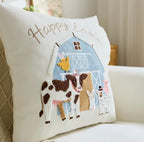 Decorative pillow with farm scene and 'Happy Easter' text on a couch.