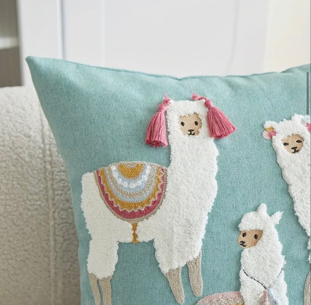Decorative pillow with embroidered llamas on a light blue background
