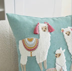 Decorative pillow with embroidered llamas on a light blue background