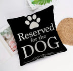Black pillow with 'Reserved for the DOG' text and paw print on a white surface.