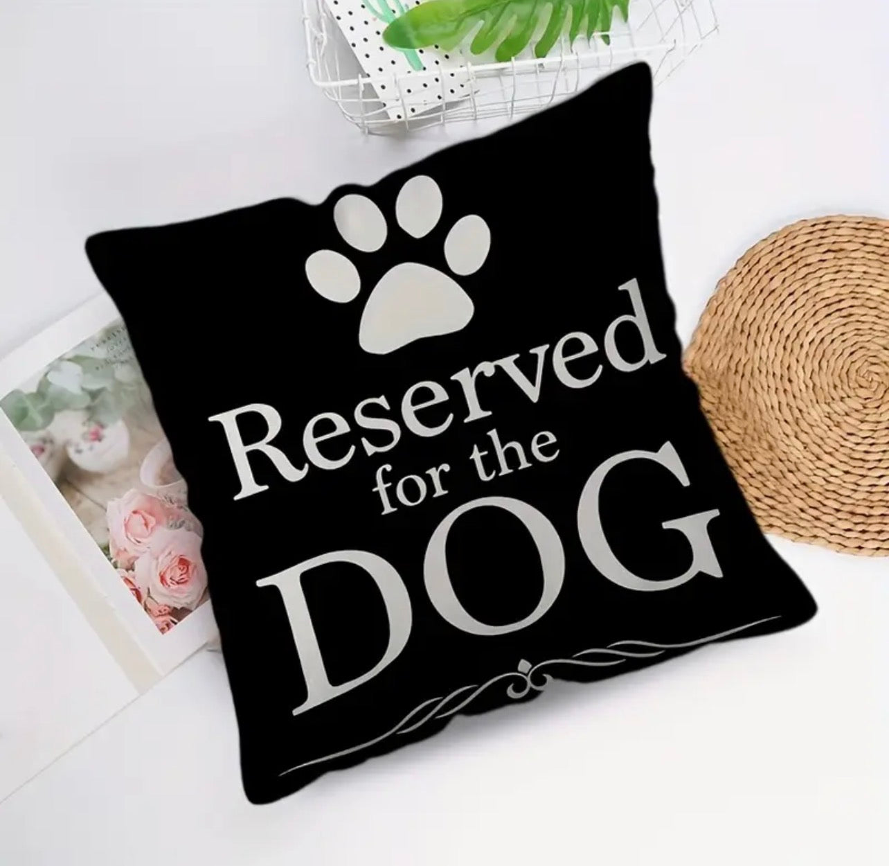 Black pillow with 'Reserved for the DOG' text and paw print on a white surface.