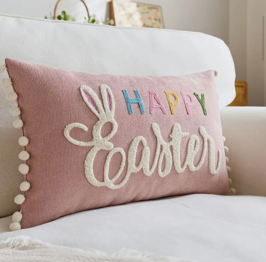 Pink 'Happy Easter' pillow with bunny design on a white couch.