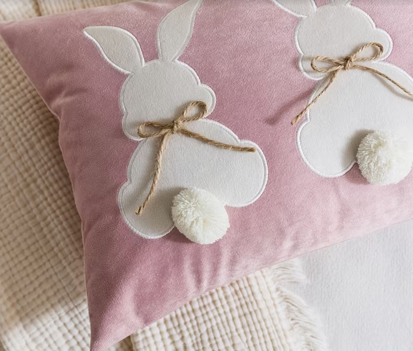 Pink pillow with white bunny decorations on a soft surface