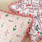 Two decorative pillows with floral and bow pattern on a beige surface