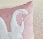 White bunny ear on a pink easter cushion on a cream sofa