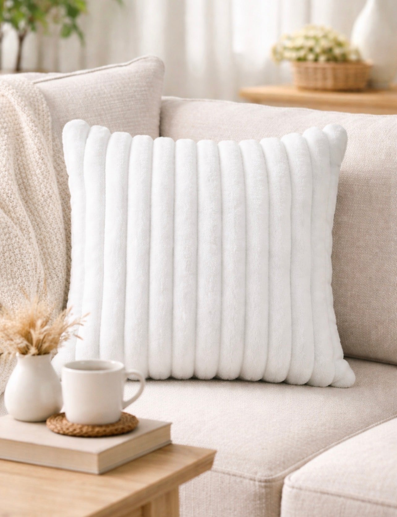 White textured pillow on a beige sofa with a small table and decor items in the background.