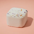 Square bath bomb with decorative elements on a pink background