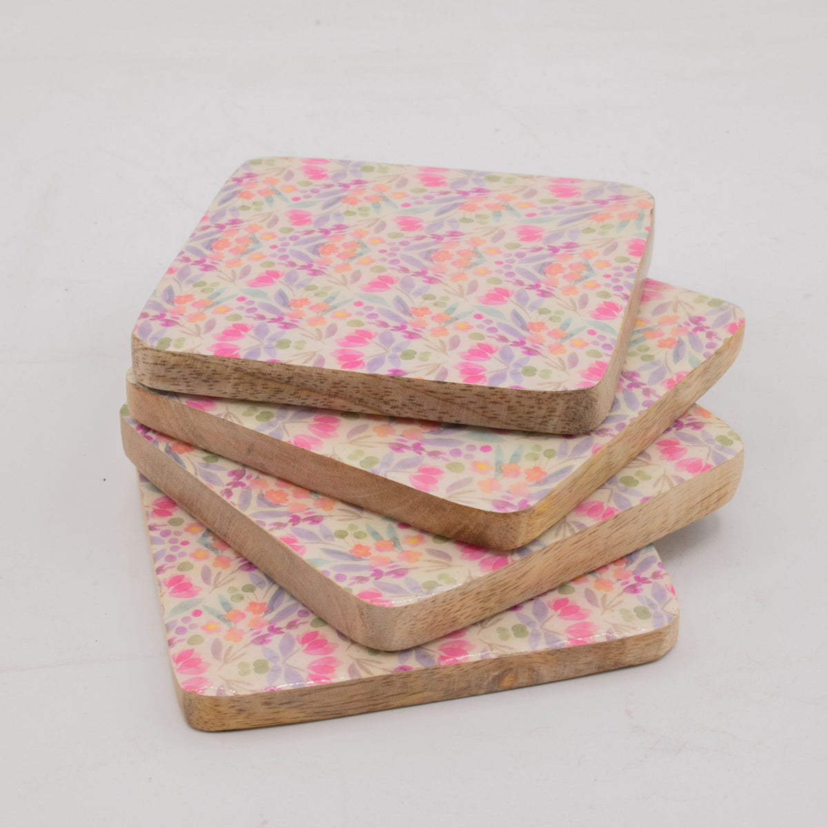 Set of four floral patterned coasters on a light gray background