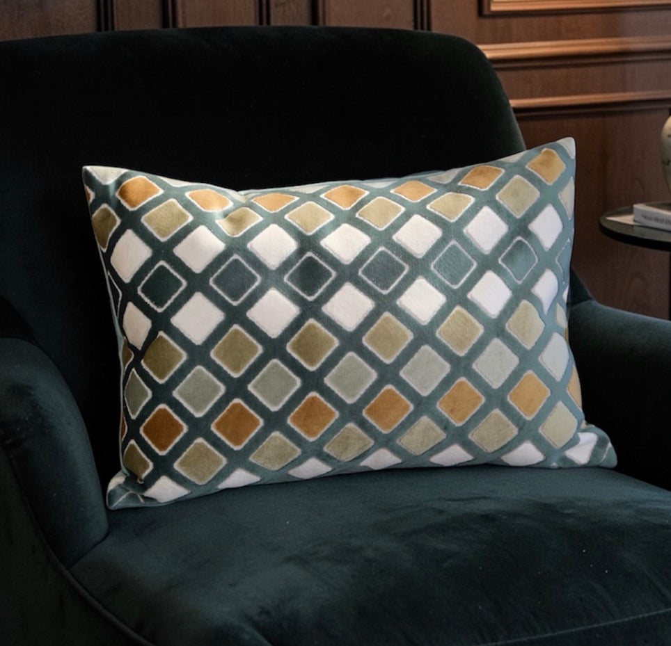 Decorative pillow with geometric pattern on a dark green armchair.
