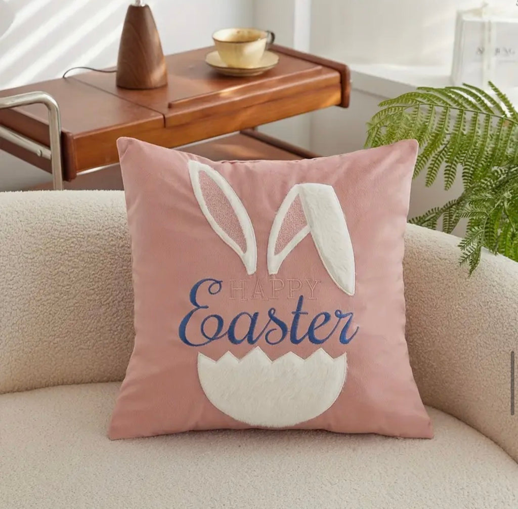 Pink pillow with 'Happy Easter' text and bunny ears on a beige couch.
