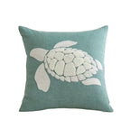 Teal pillow with a white turtle design on a white background