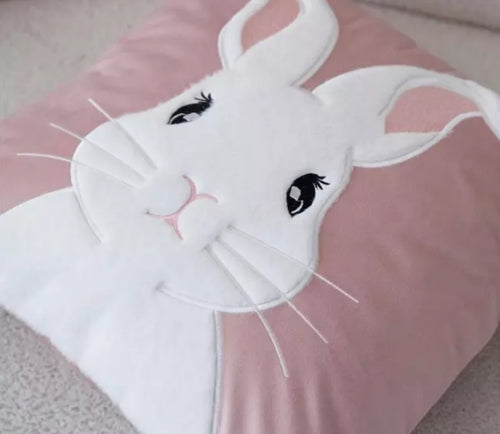 White easter bunny on a pink velvet cushion on a sofa